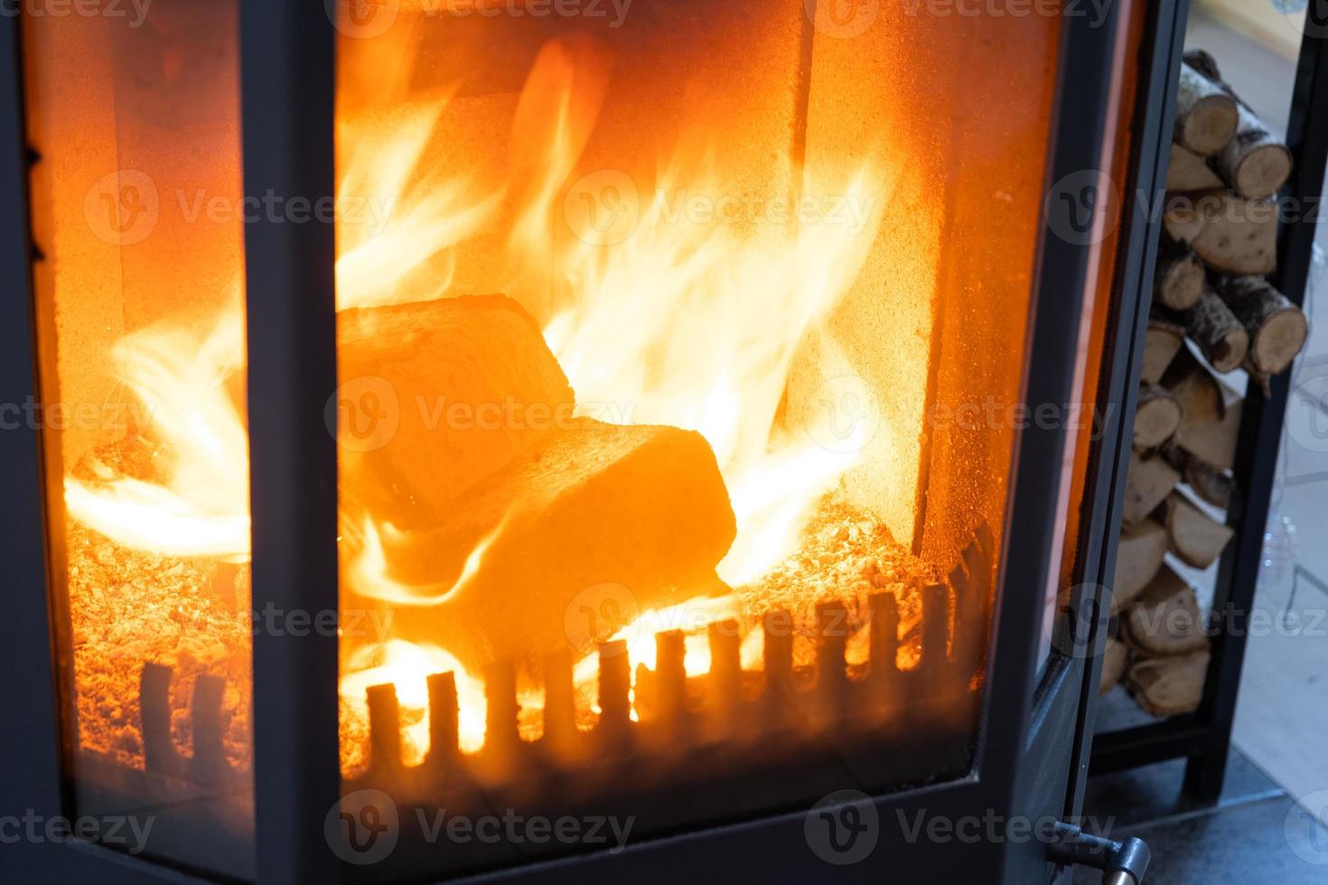 Fuel briquettes made of pressed sawdust for kindling the furnace - economical alternative eco-friendly fuel for the fireplace in the house. Firewood is burning in the oven in the interior photo