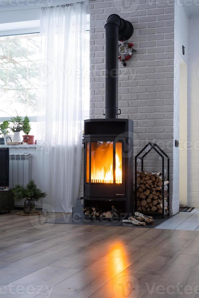 estufa negra, chimenea en el interior de la casa en estilo loft. calefacción ecológica alternativa, habitación cálida y acogedora en casa, madera quemada foto