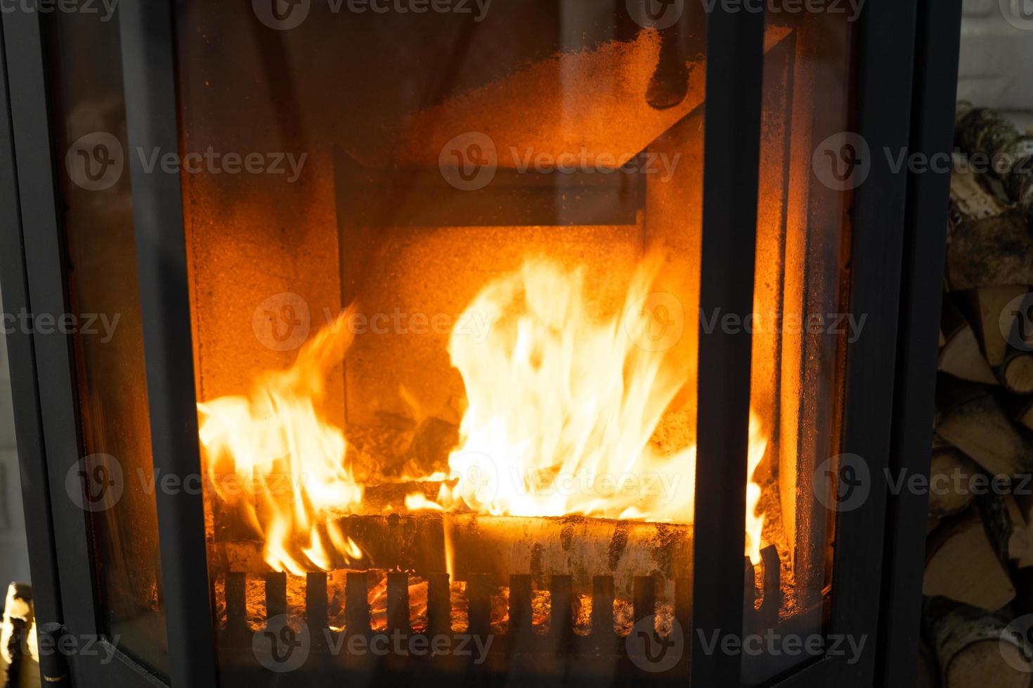 Firewood is burning in the furnace of the hearth close-up. Alternative eco-friendly heating, warm cozy room at home, burning wood photo