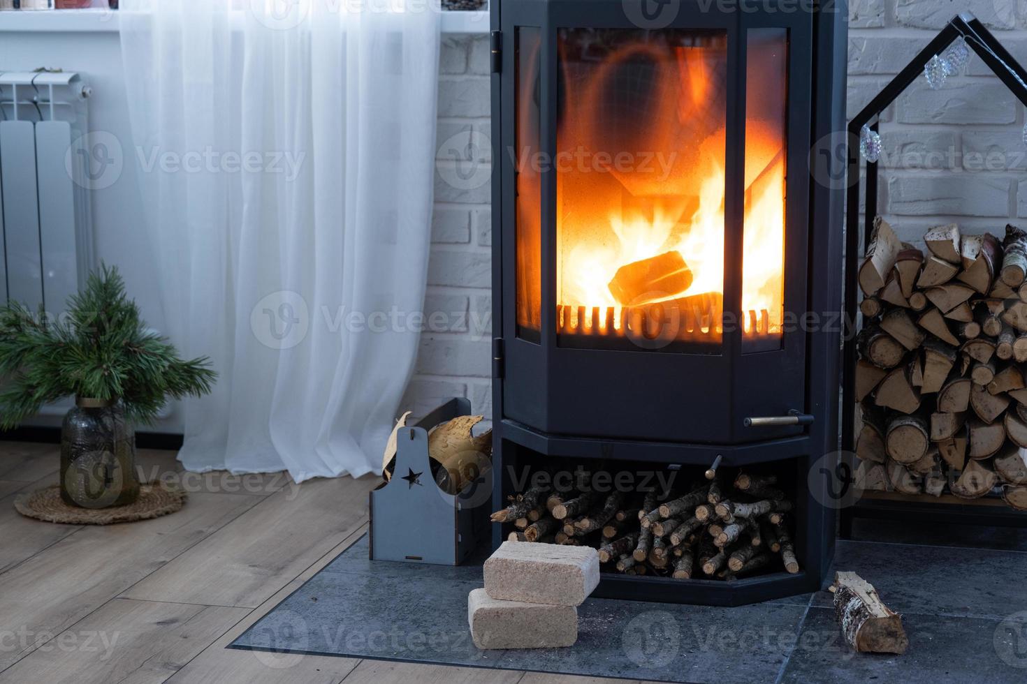 Fuel briquettes made of pressed sawdust for kindling the furnace - economical alternative eco-friendly fuel for the fireplace in the house. Firewood is burning in the oven in the interior photo