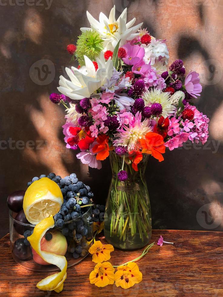 Bouquet with dahlias, phlox, nasturtium, gomphrena, eucomis, grapes and lemon photo