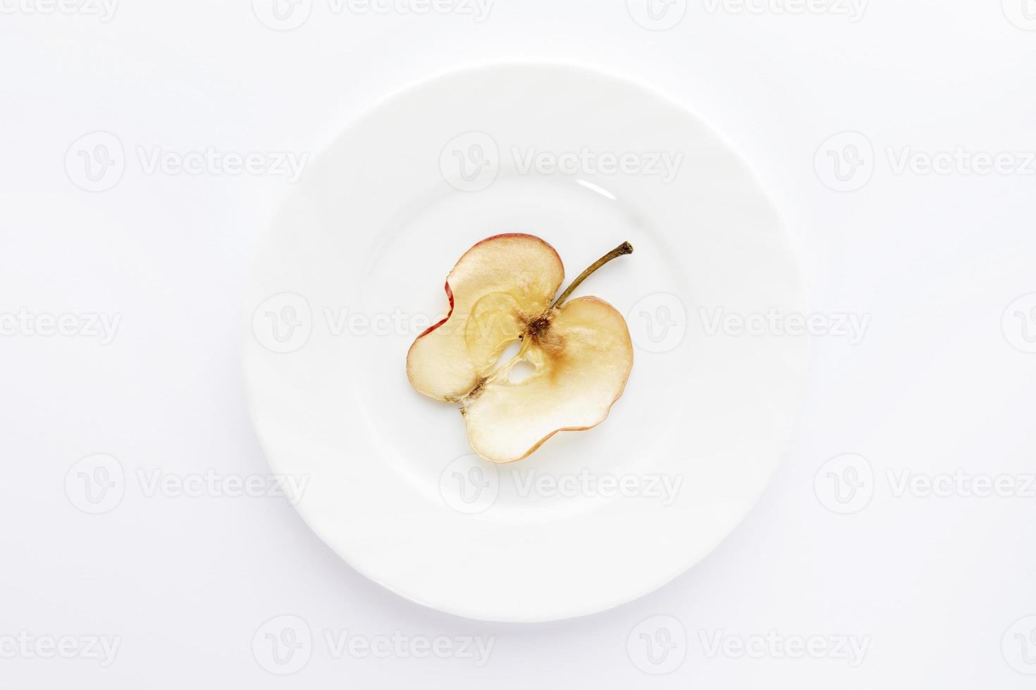 One thin slice of dried apple on round white plate on white background. photo