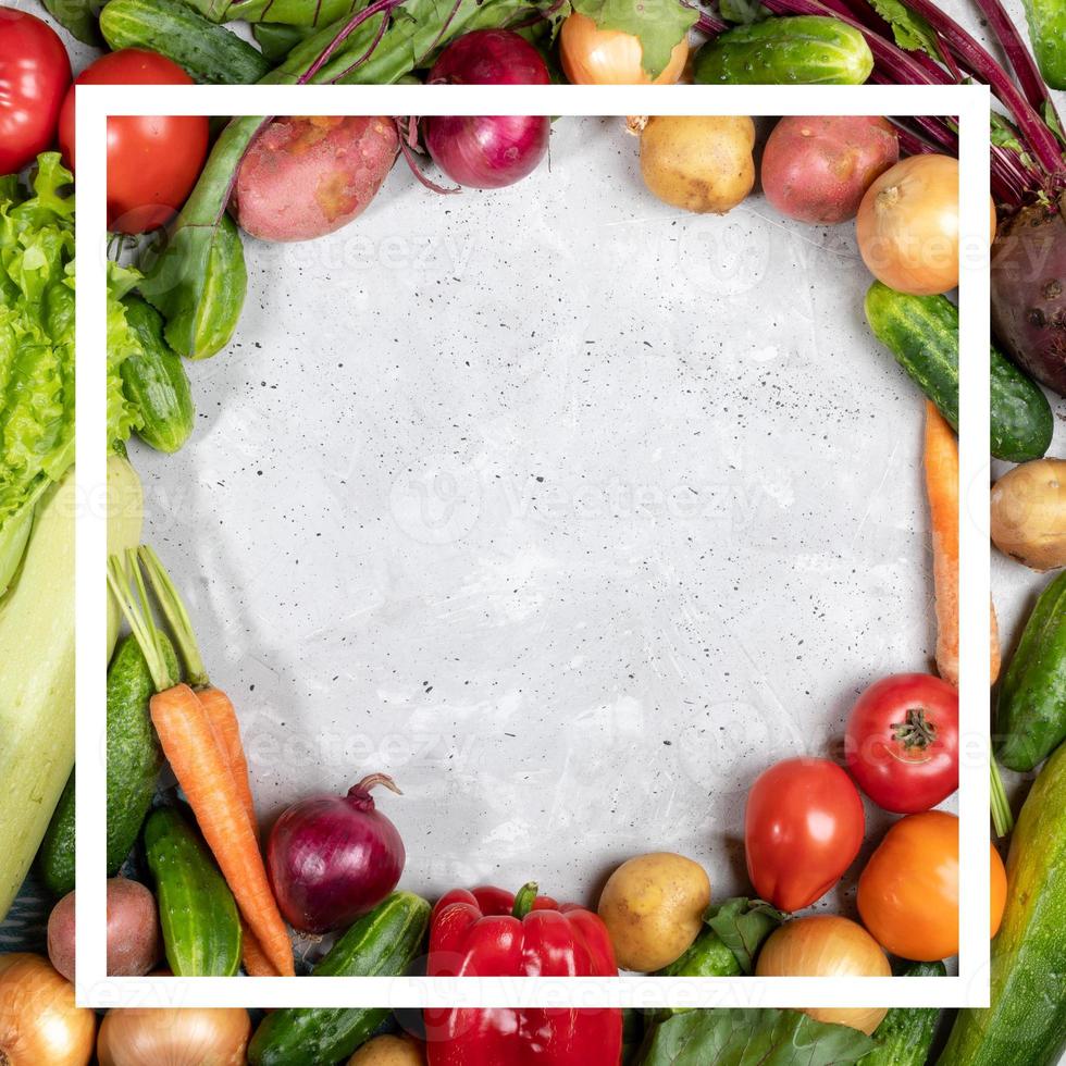 Frame by vegetables and creative white square frame on them on concrete background with copy space. photo