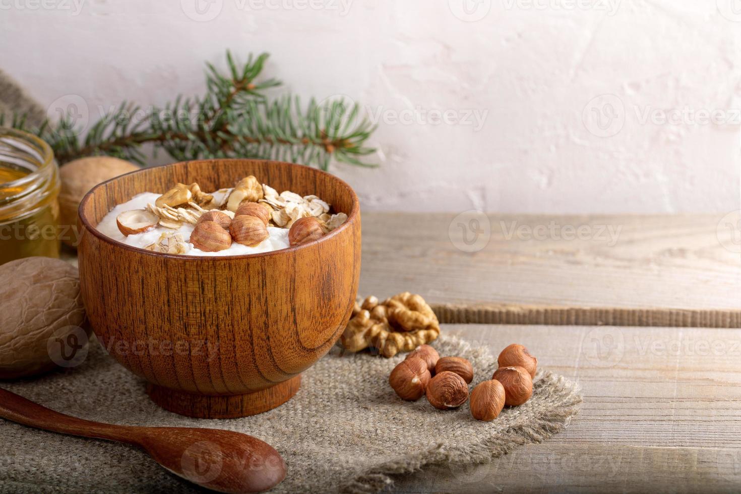 cuenco de madera con yogur casero blanco y nueces sobre arpillera sobre tablones de madera. foto