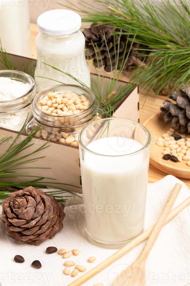 Vegan cedar milk, ingredients nuts and flour in jars, cones, branches, spoon. Selective focus. photo