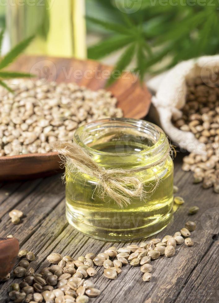 composición con productos de cáñamo. aceite de cannabis, semillas y hojas verdes en una vieja tabla de madera. foto