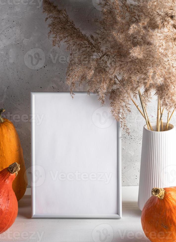 Empty white frame with space for text, pumpkins, dry grass on light neutral background. Mock up. photo