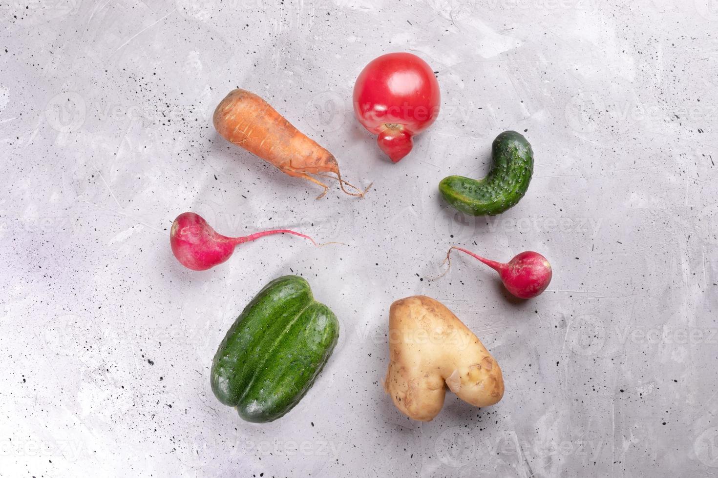 Set of ugly vegetables laid out in circle on concrete background. photo