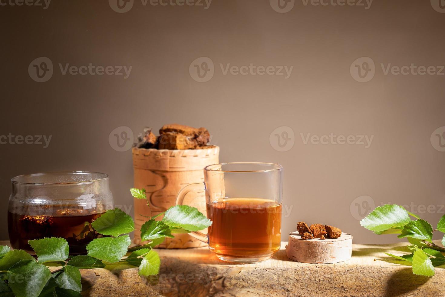 Healing beverage from birch mushroom chaga, chaga mushroom pieces, twigs on wooden plank on beige backdrop. Copy space. photo