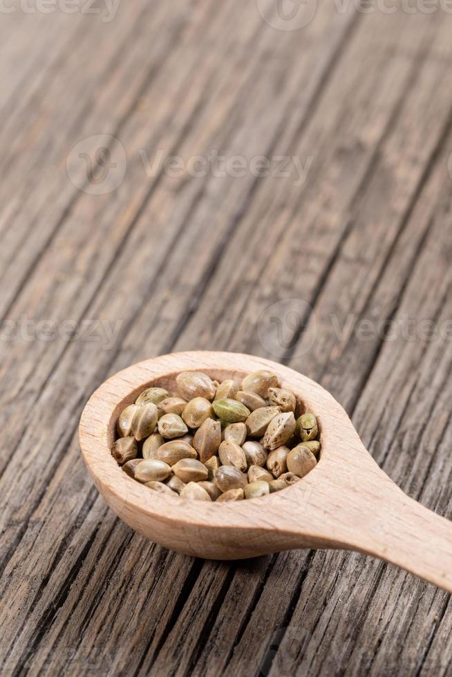 One wooden spoon with cannabis seeds  on diagonal old wooden boards. photo