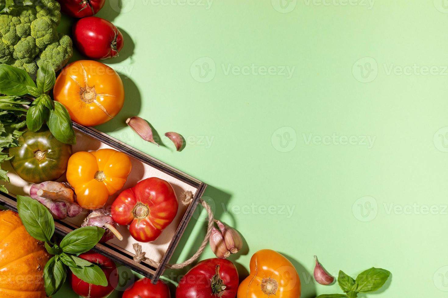 Top view harvest of farm vegetables in small wooden box and on pastel green background. View above. Copy space for text. photo