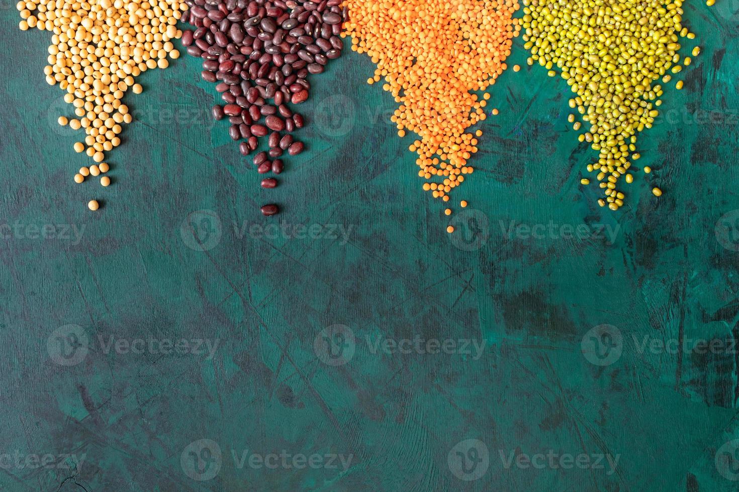 Emerald-green background with scattered in triangular piles on it legumes. photo