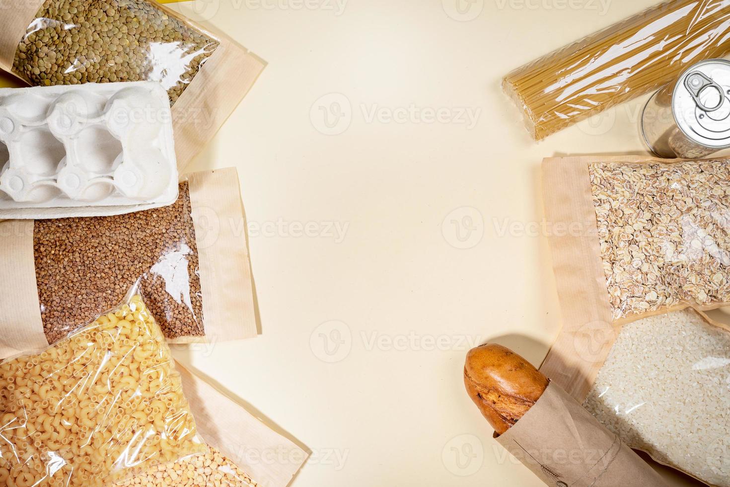Stock of food products in eco-friendly paper and cellophane packagings laid out on beige backdrop. Top view, copy space. photo