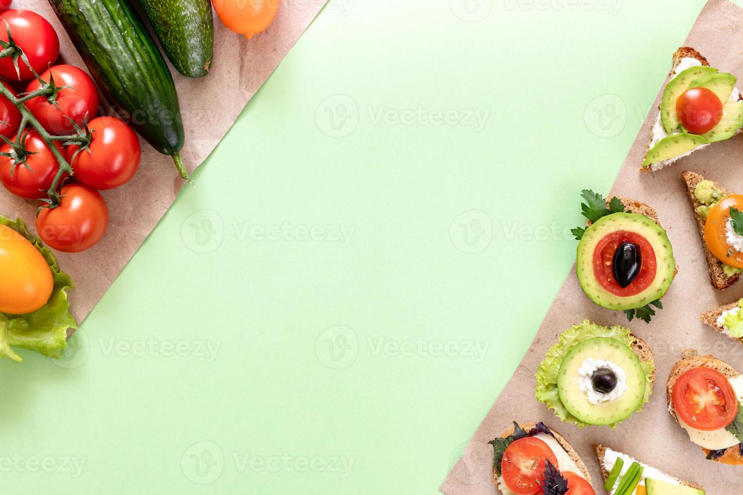 Vegetables and vegetarian sandwiches are lying on wrapping paper pieces on green background with copy space. photo