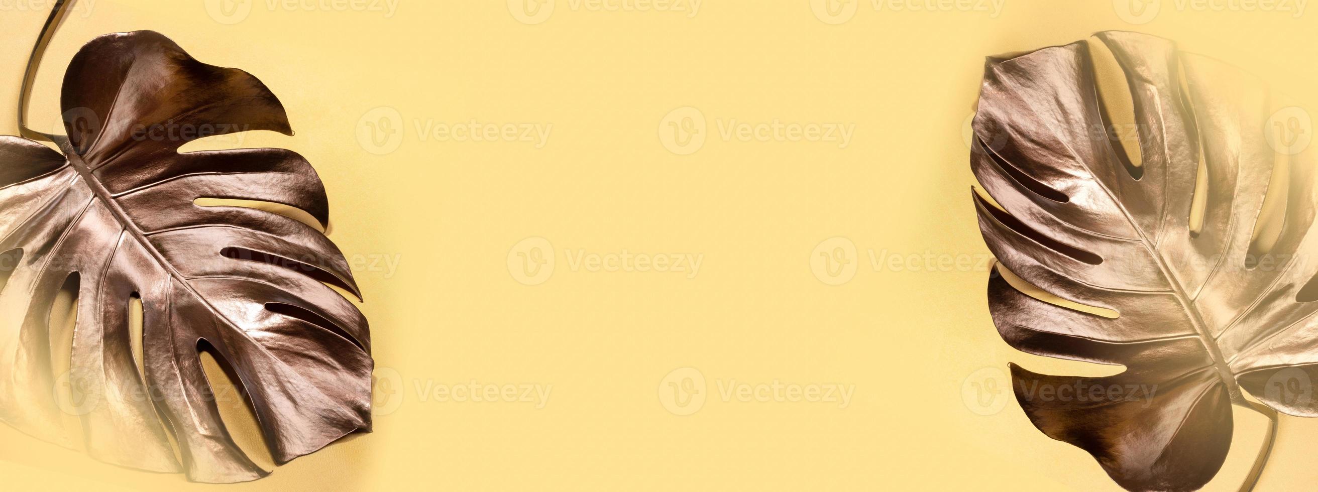 Luxury advertising top view golden banner with two bronze monstera leaves and copy space in center. photo
