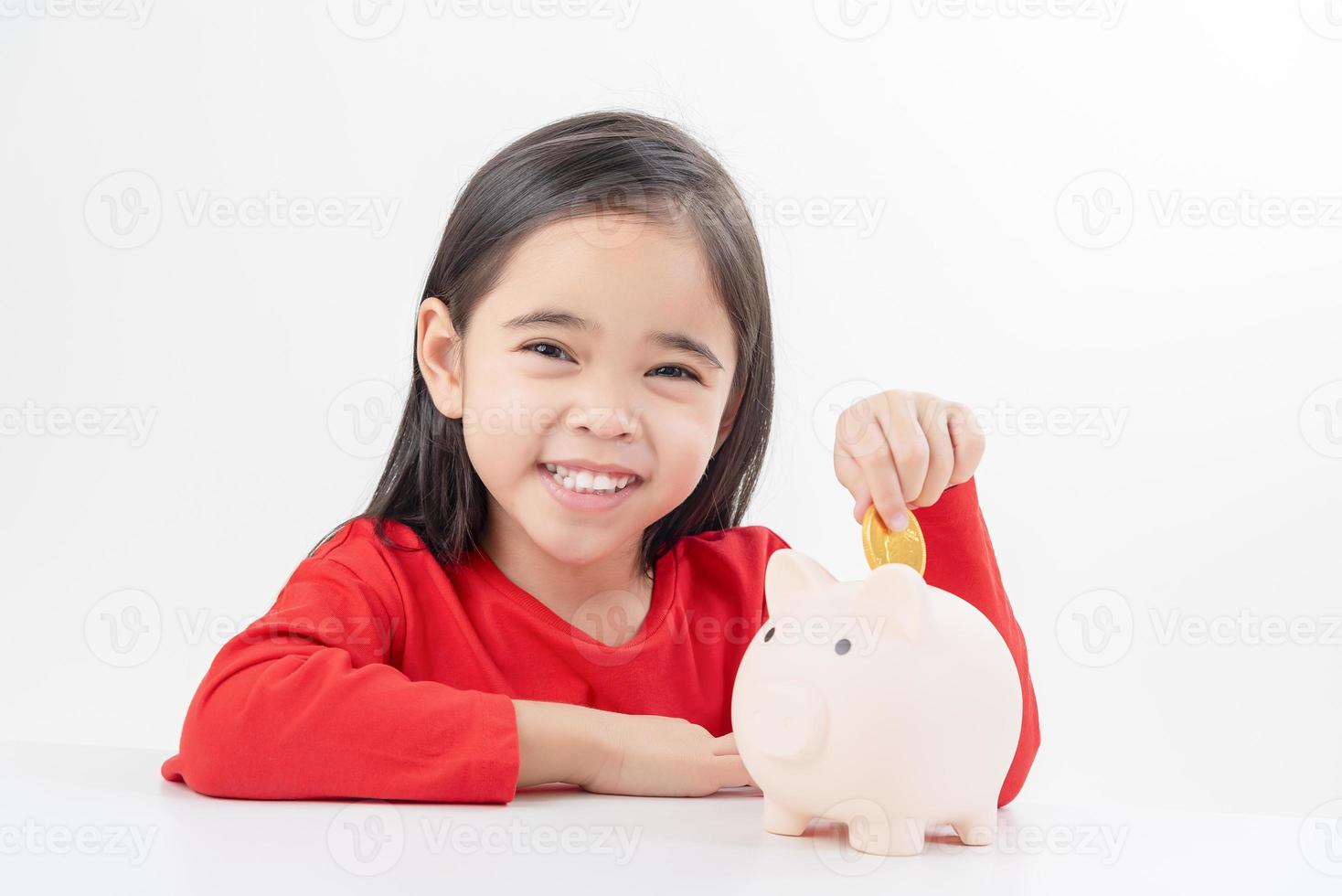 Little Asian girl saving money in a piggy bank, learning about saving, Kid save money for future education. Money, finances, insurance, and people concept photo