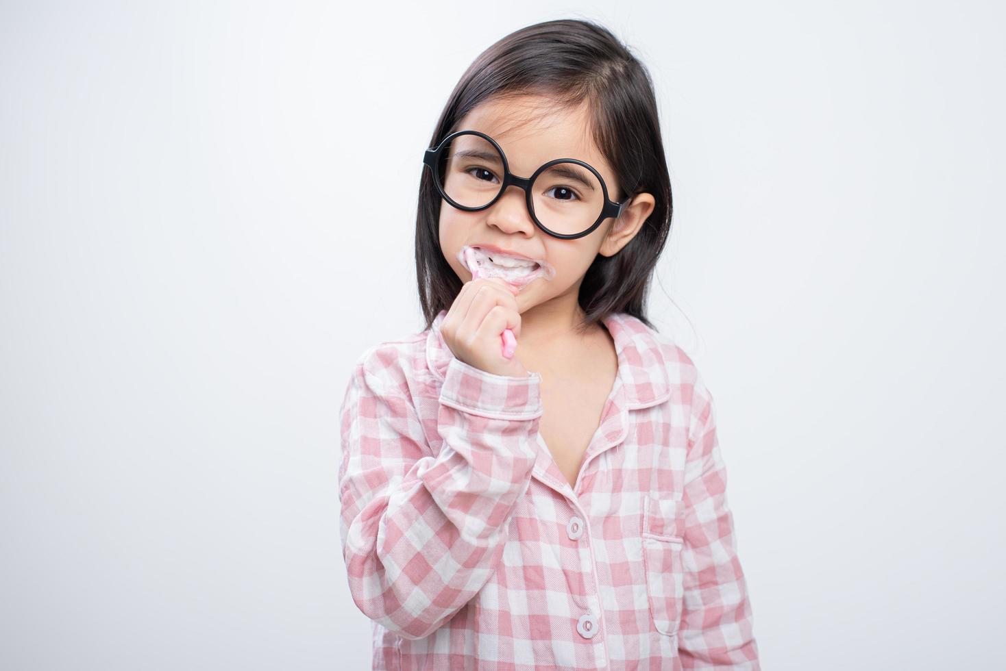 little girl Asia brushing teeth happily white background photo