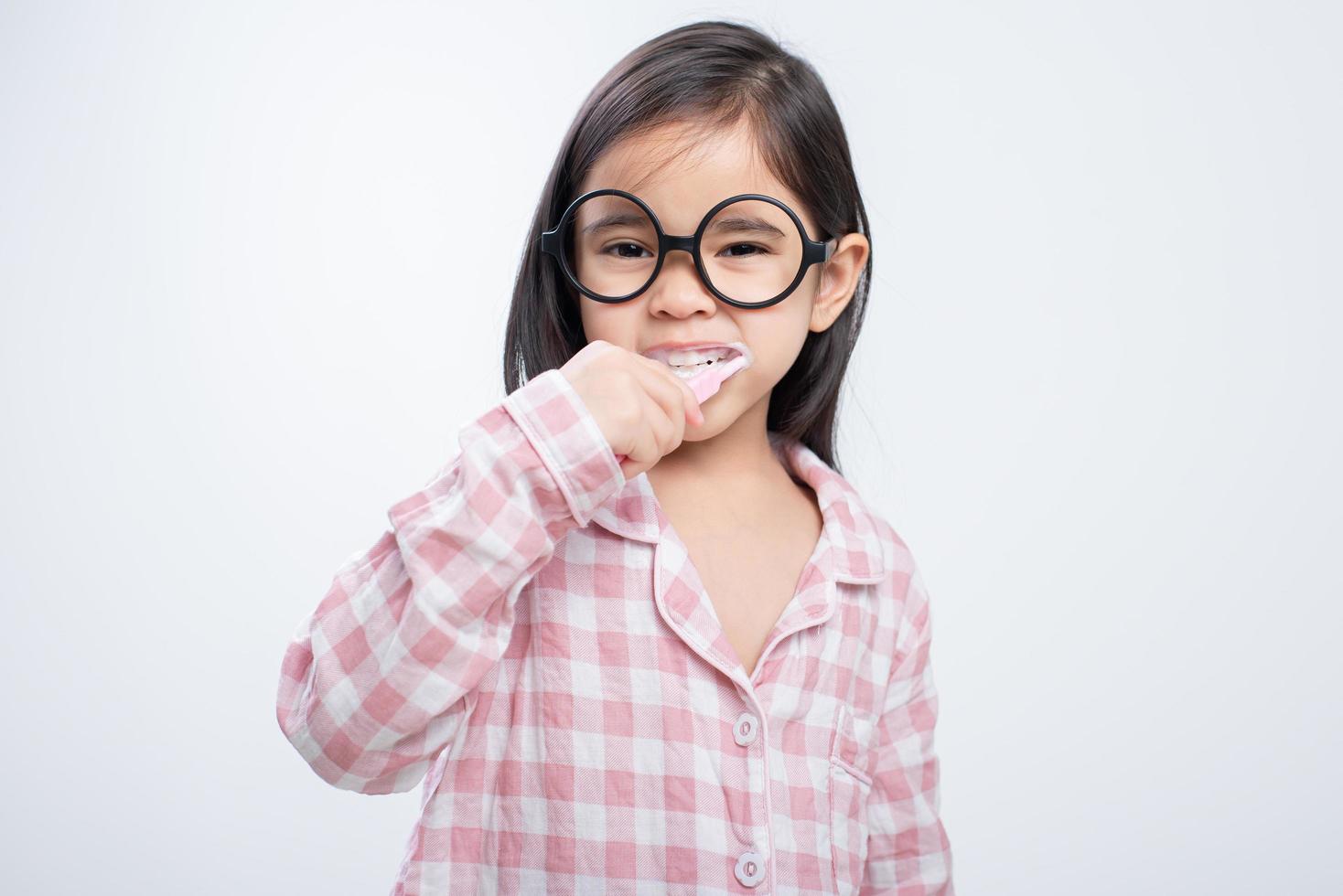 little girl Asia brushing teeth happily white background photo