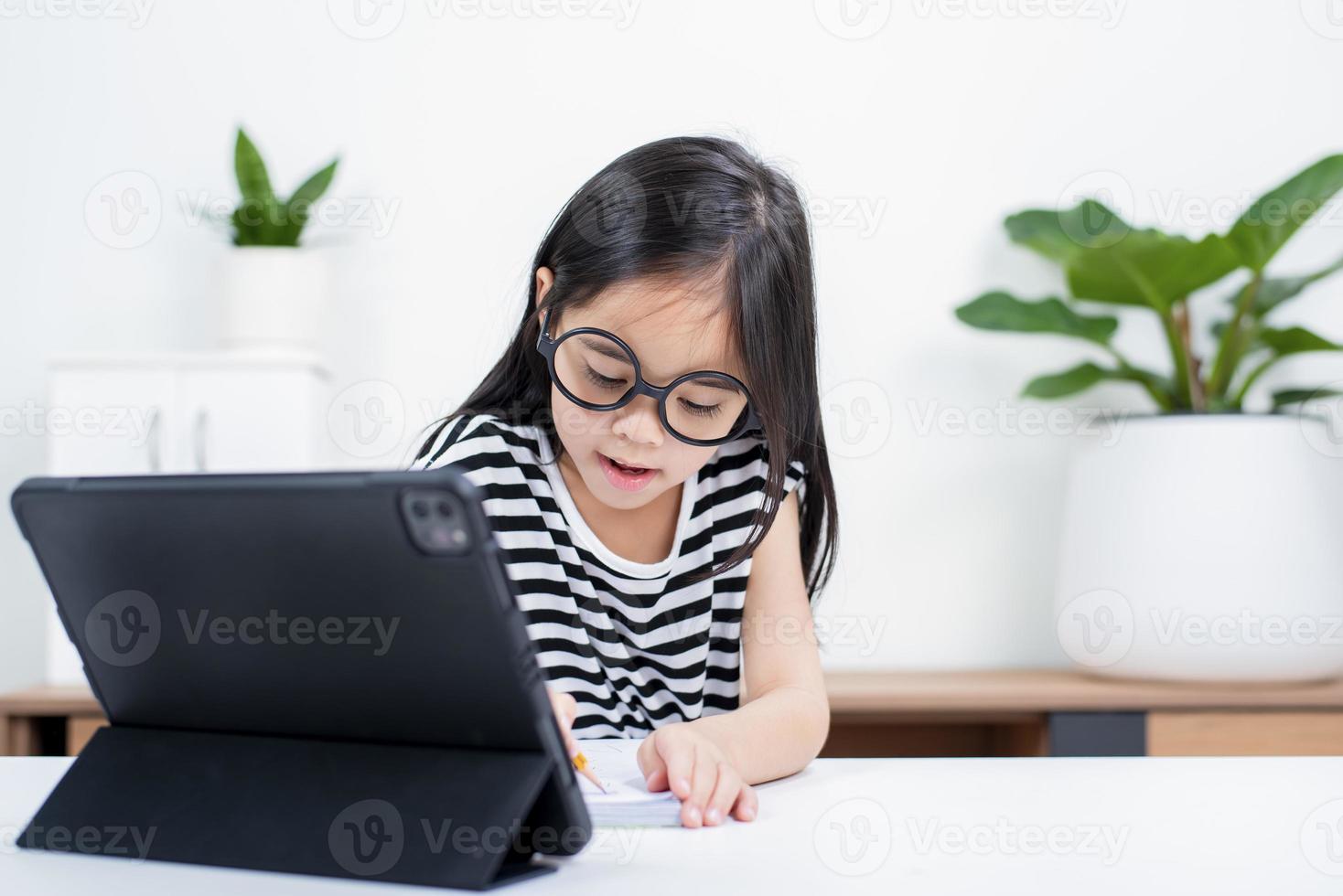 Asian child girl student wow excited on video call learning to studying online class or person learn from home school with tablet photo