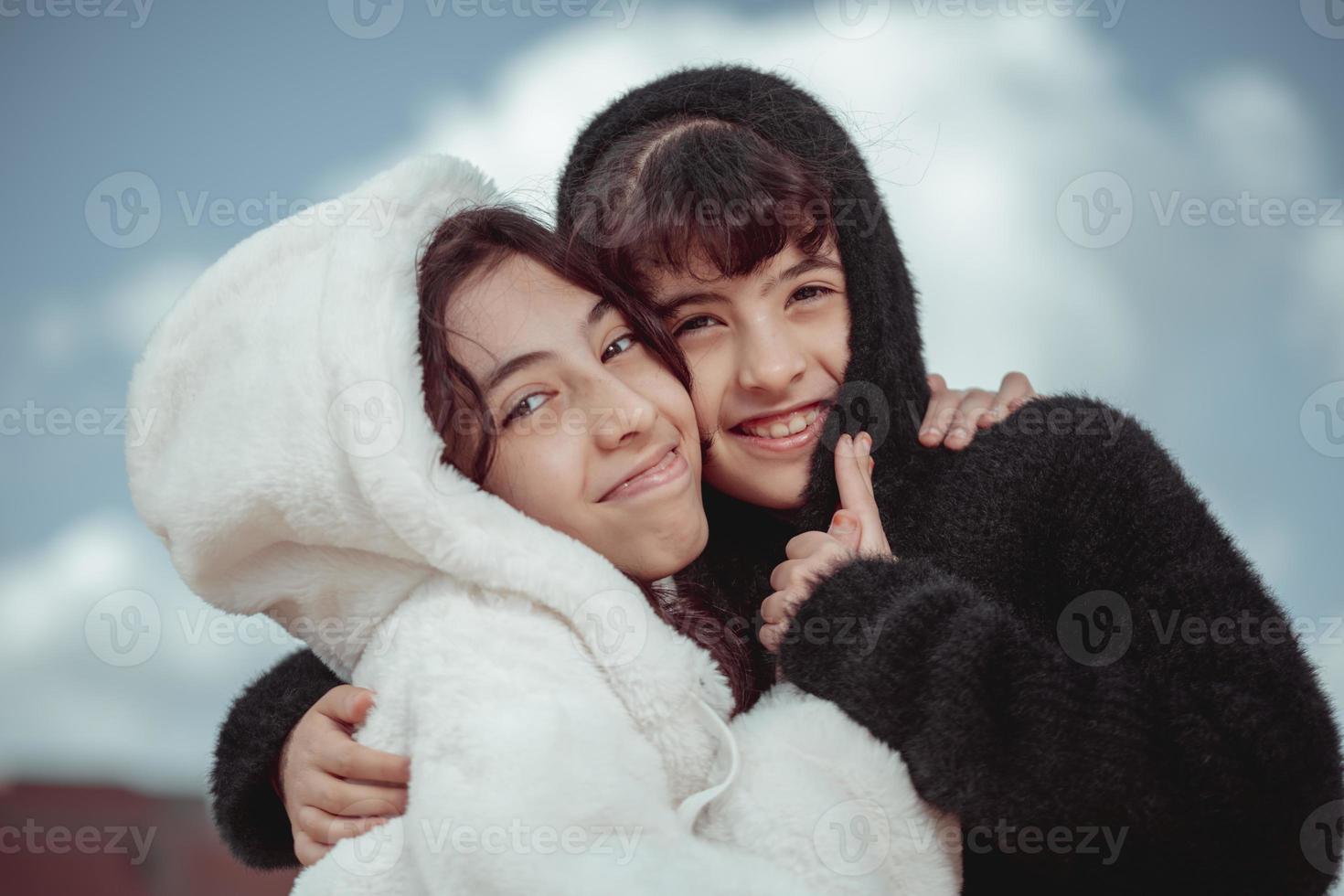 retrato de dos hermanas con una chaqueta de piel blanca y negra, felices en invierno foto