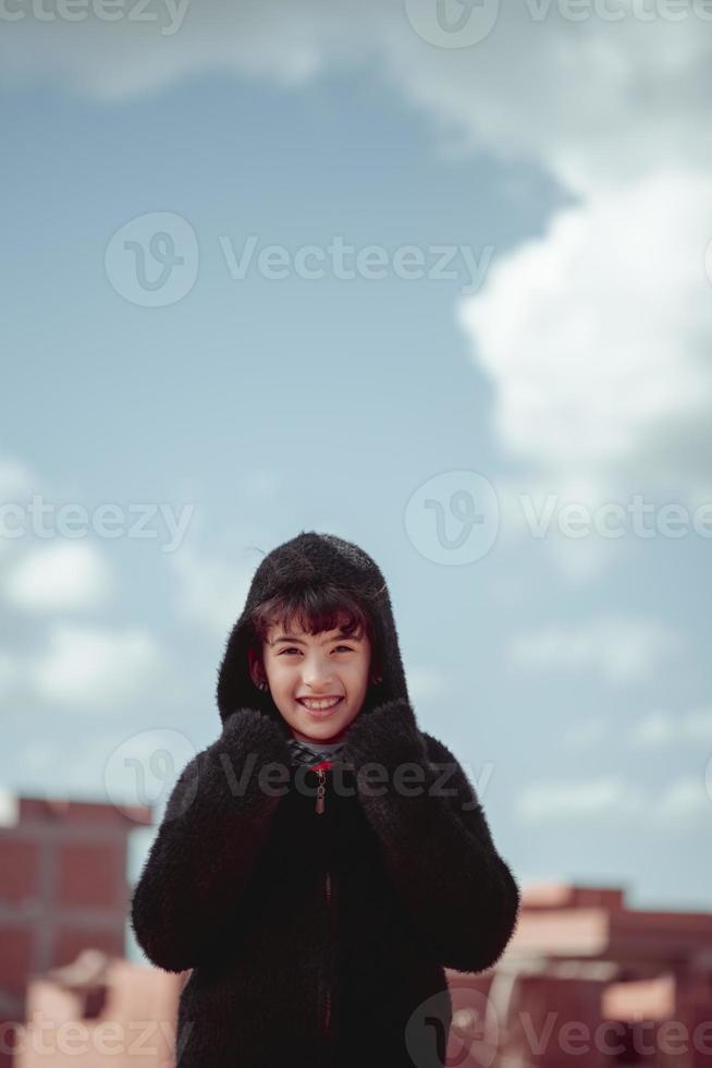 retrato de una hermosa niña con una chaqueta de piel bajo un cielo azul foto