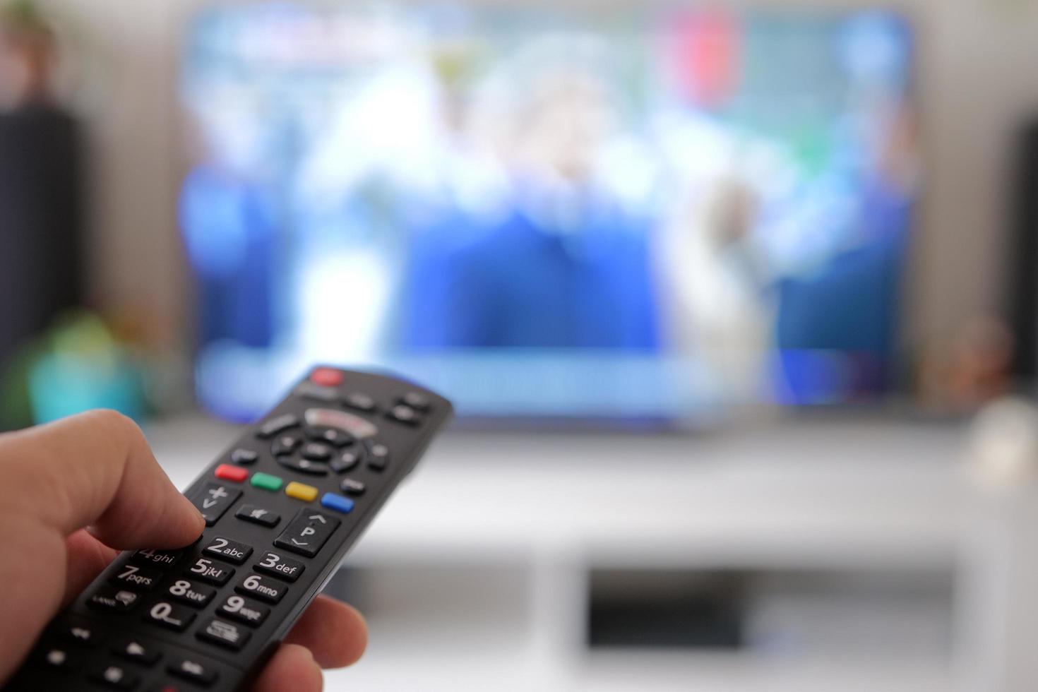 Select the channel with remote control to watch a movie on TV at home photo