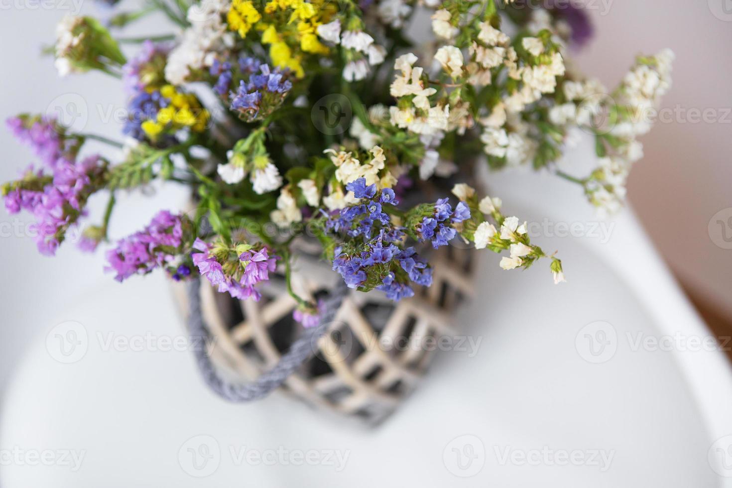 Dried flowers in a wooden vase stands on a white chair, copy space. Place for an inscription. photo