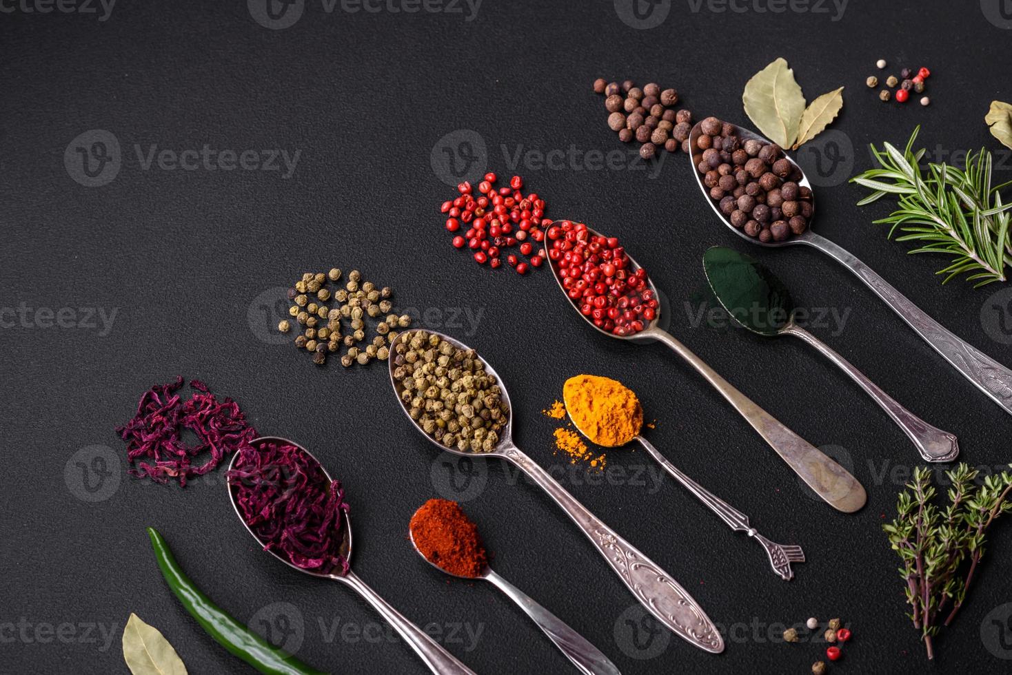 Several types of spices in metal spoons paprika, tomatoes, curry, beets, cumin, turmeric, fennel, spirulina photo