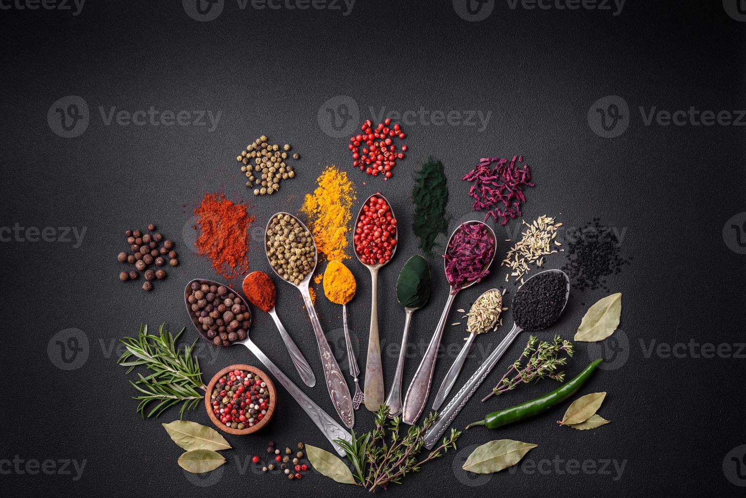 Several types of spices in metal spoons paprika, tomatoes, curry, beets, cumin, turmeric, fennel, spirulina photo