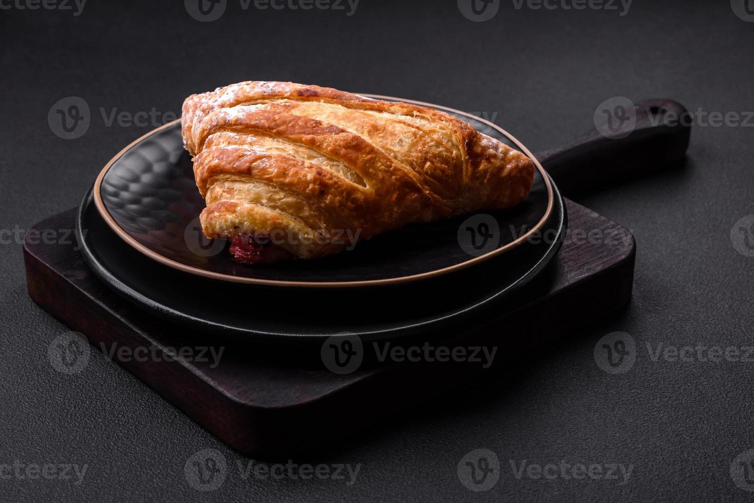 Delicious fresh crispy bun with jam on a black ceramic plate photo