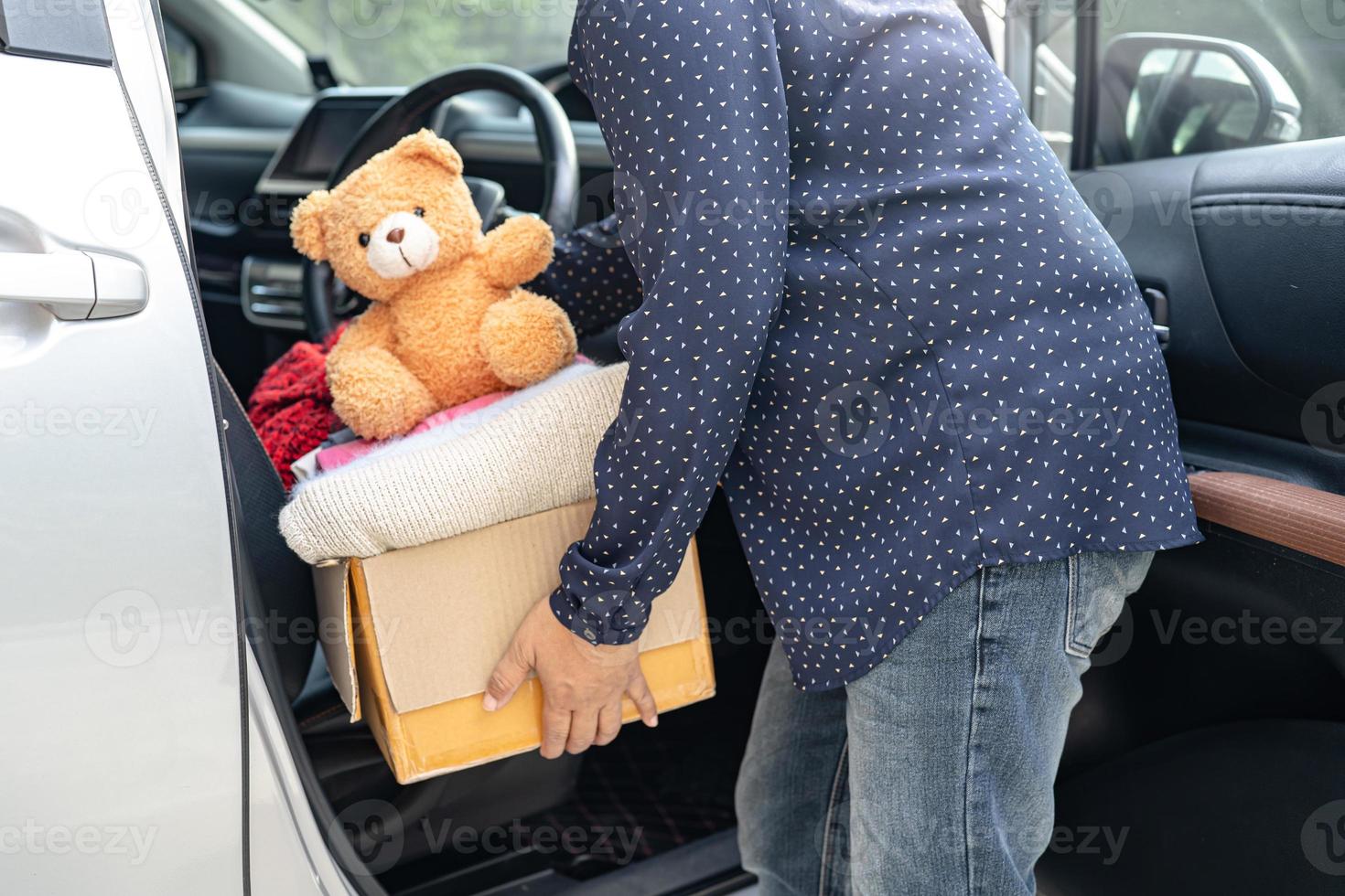 Mujer voluntaria proporciona caja de donación de ropa con ropa usada y muñecas en casa para apoyar la ayuda a refugiados, personas sin hogar o pobres en el mundo. foto