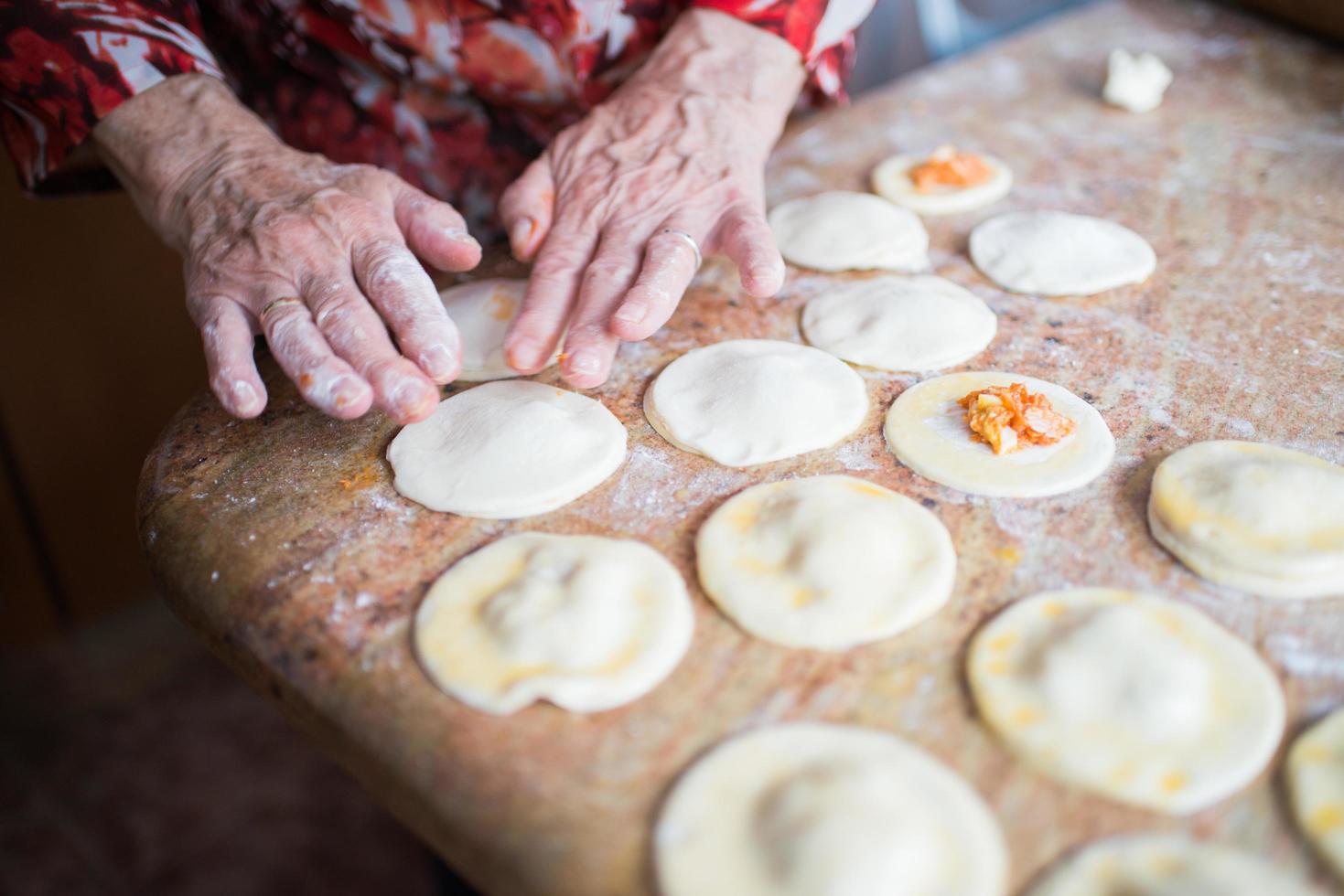 manos humanas llenando y sellando bolas de masa de hojaldre foto