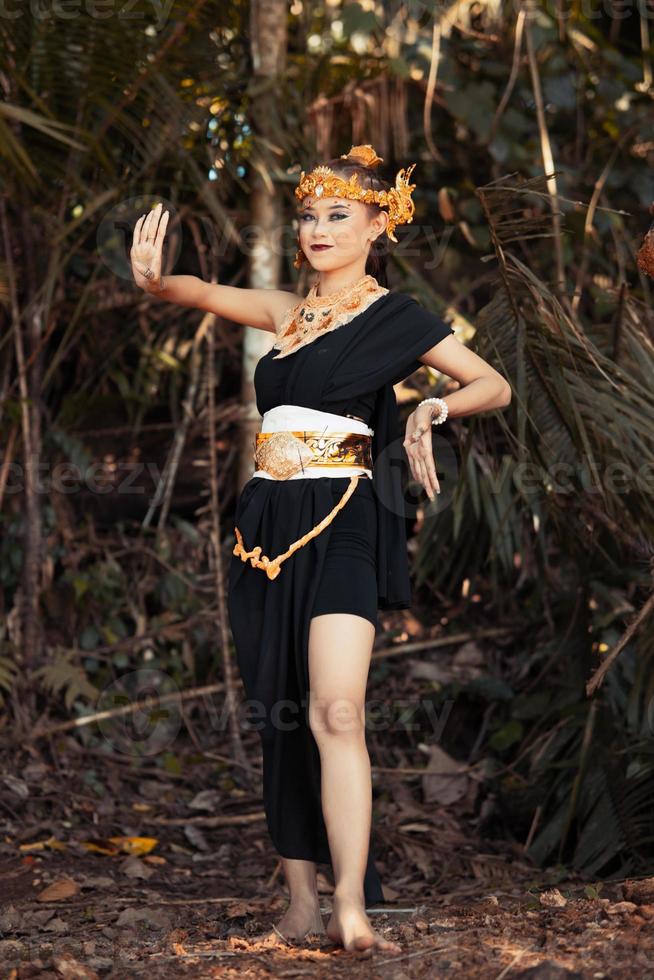 The face of an Asian woman with golden jewelry on her body while wearing a black costume with a happy face photo