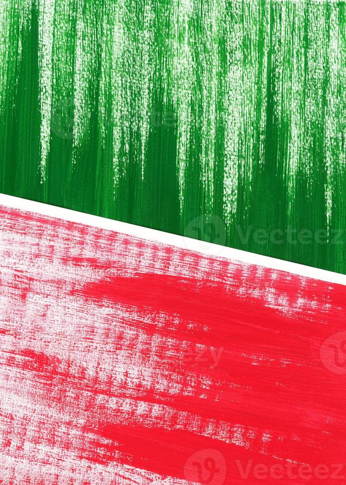 Two abstract drawings lie on on surface, overlapping each other. Acrylic or gouache green and red paint on texture paper. Brushstrokes of paint. Partially visible, selective focus, close up. photo