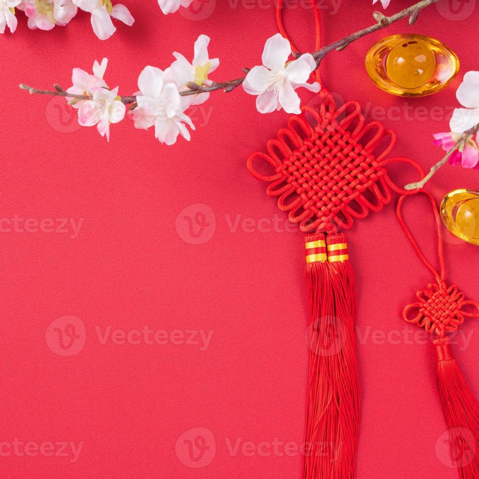 Design concept of Chinese lunar new year - Beautiful Chinese knot with plum blossom isolated on red background, flat lay, top view, overhead layout. photo