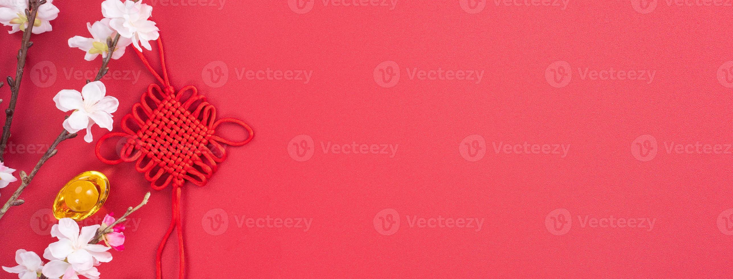 Design concept of Chinese lunar new year - Beautiful Chinese knot with plum blossom isolated on red background, flat lay, top view, overhead layout. photo