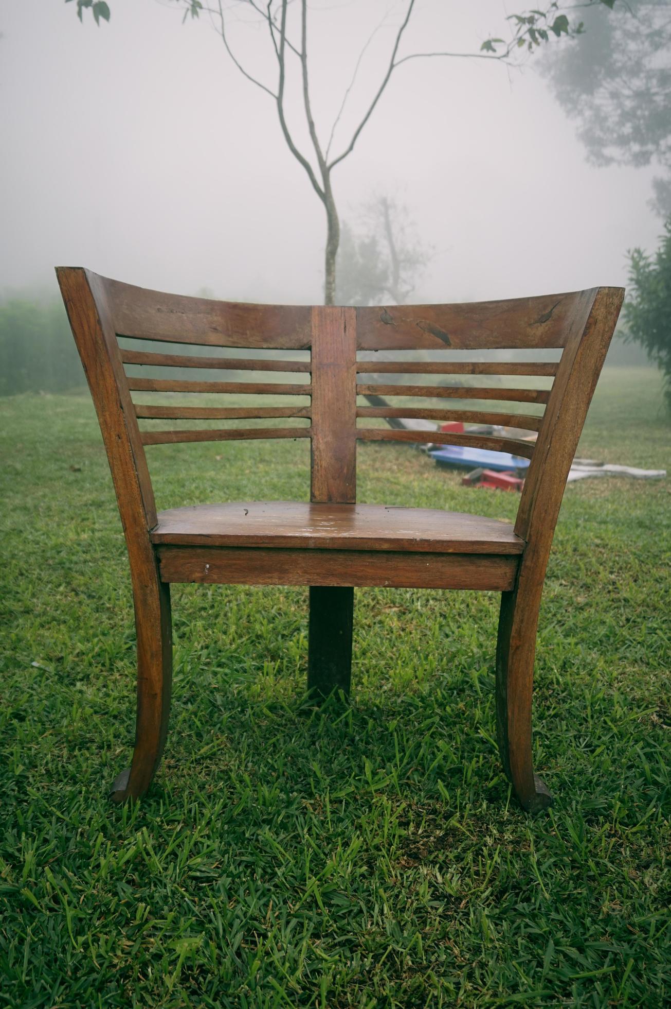 Round wooden chair in the garden with foggy background in the morning