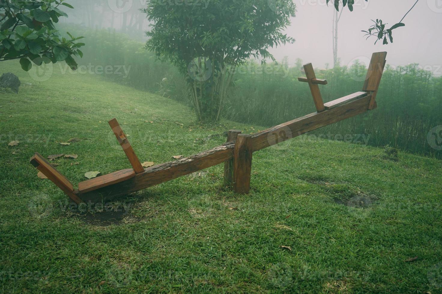 Wooden see saw in the garden with foggy background. Playground in the morning photo