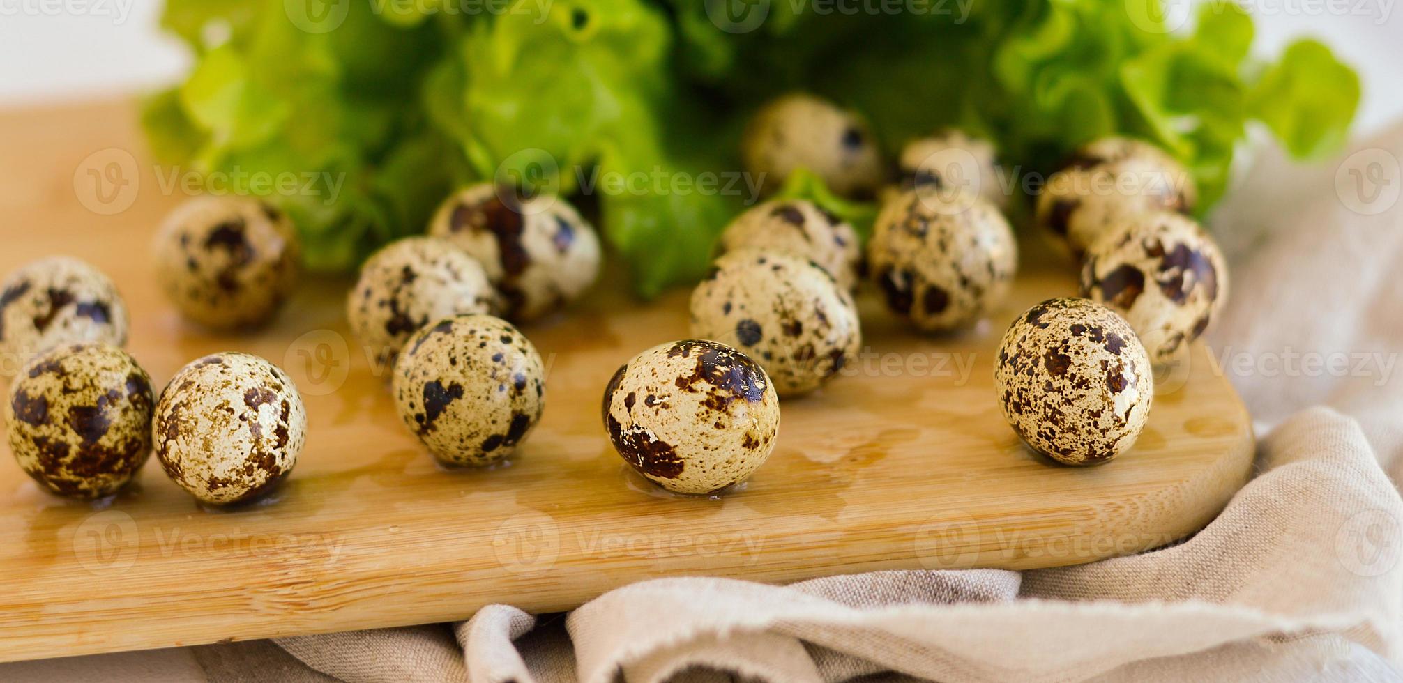 Farm quail eggs on a wooden kitchen board with green lettuce leaves.The concept of proper healthy food. photo