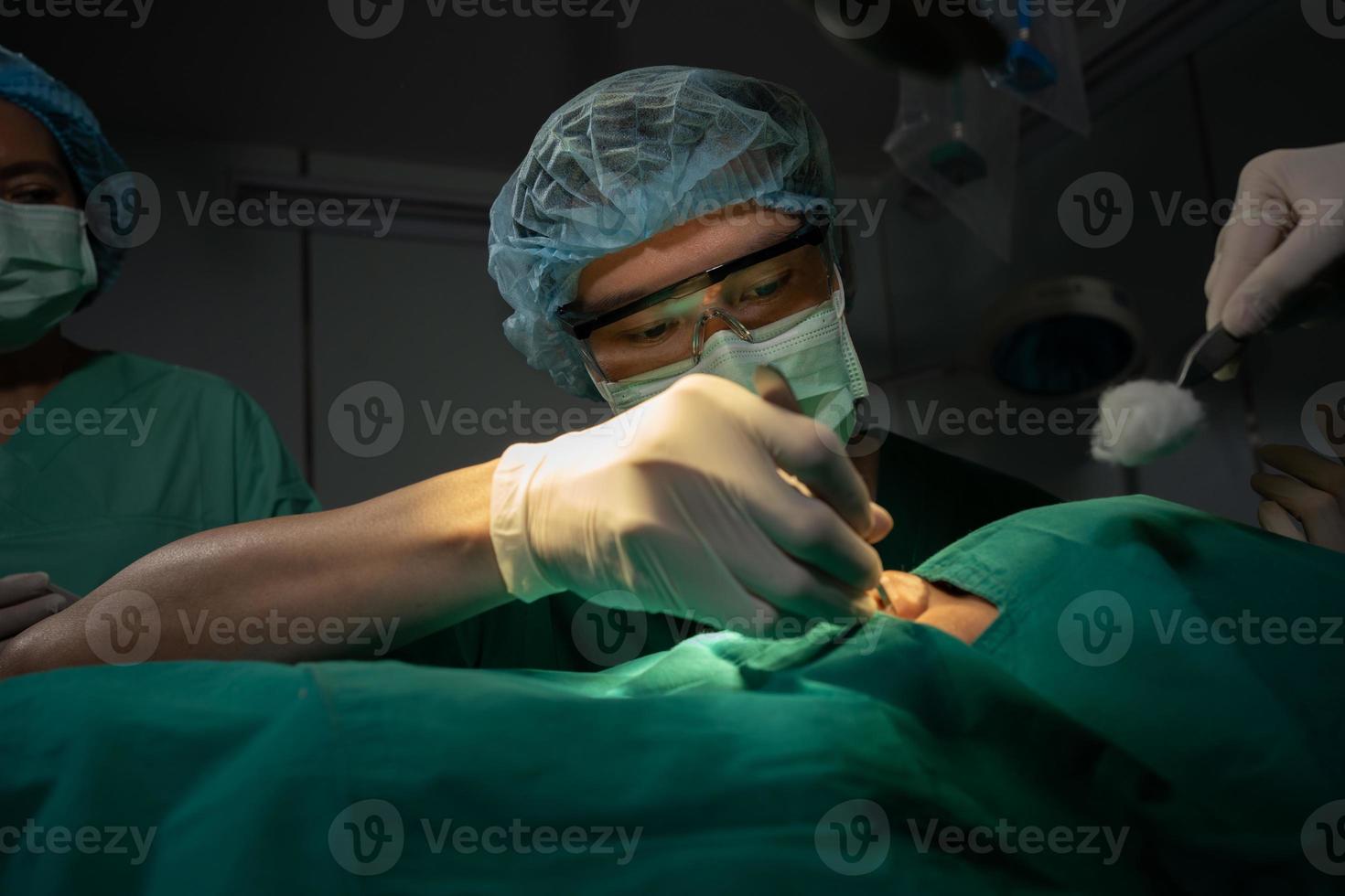Asian Professional surgeons team performing surgery in the operating room, surgeon, Assistants, and Nurses Performing Surgery on a Patient, health care cancer and disease treatment concept photo