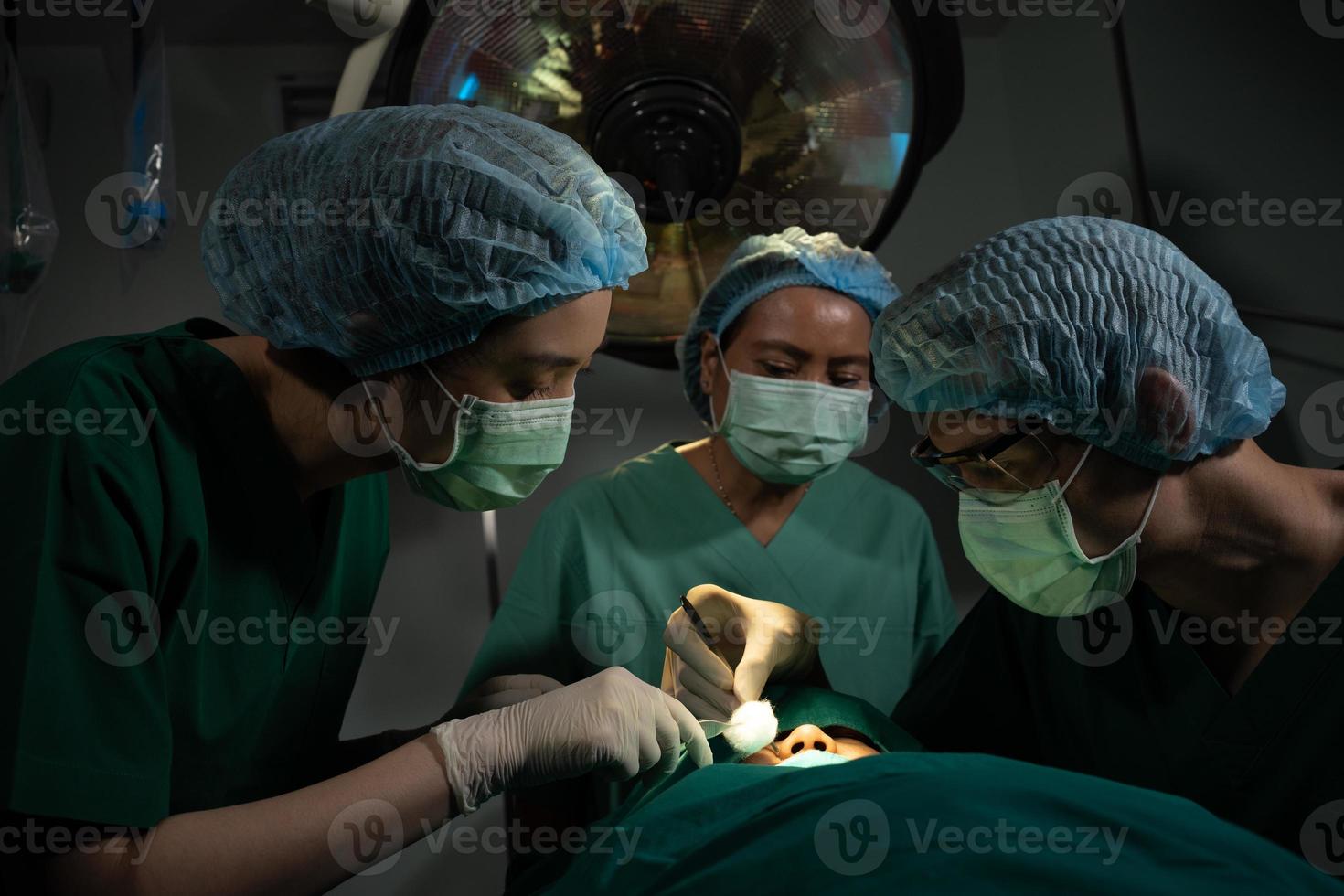 equipo de cirujanos profesionales asiáticos que realizan cirugía en el quirófano, cirujano, asistentes y enfermeras que realizan cirugía en un paciente, cáncer de atención médica y concepto de tratamiento de enfermedades foto