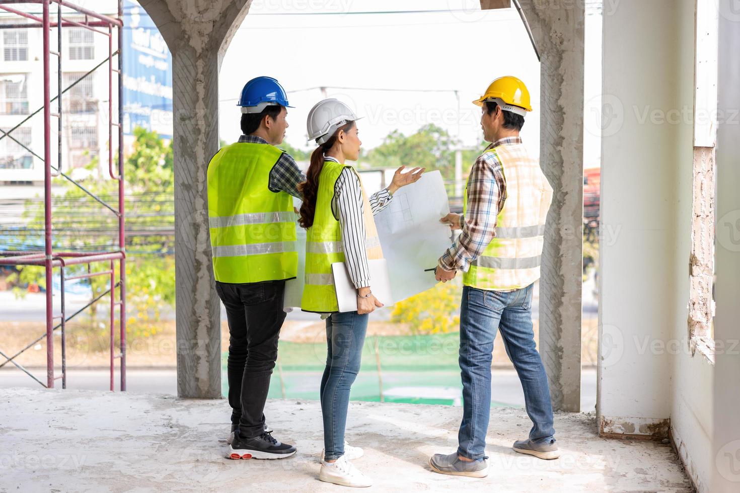 Asian engineer or Young Female Architect put on a helmet for safety and talk with a contractor on a construction building factory project, Concept of Teamwork, Leadership concept. photo