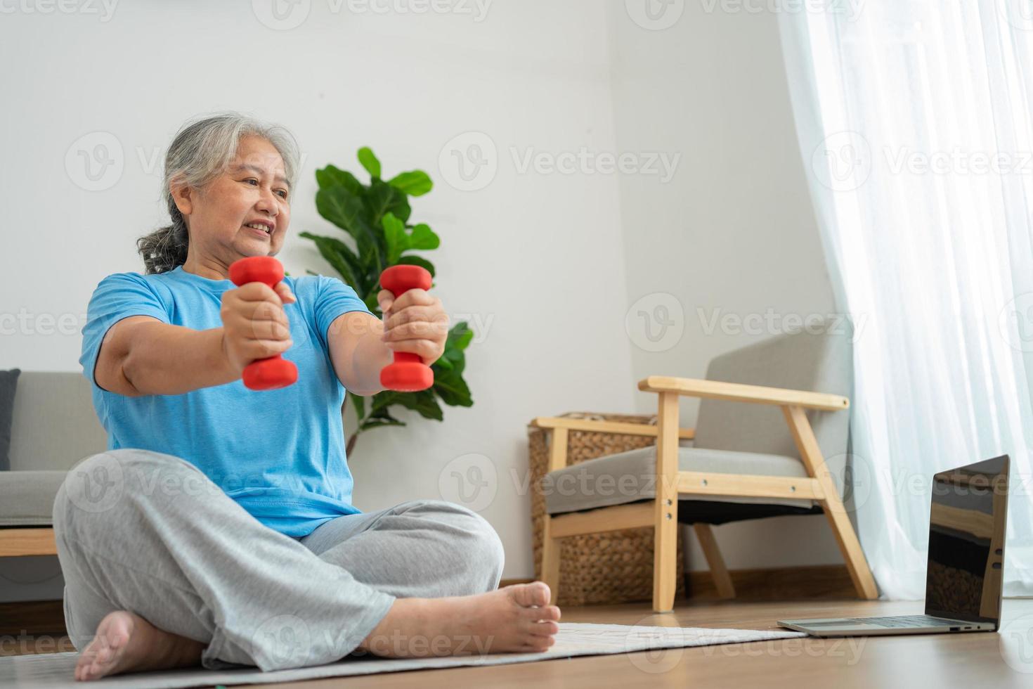 anciana asiática levantando pesas para hacer ejercicio y hacer ejercicio en casa. mujer madura activa haciendo ejercicio de estiramiento en la sala de estar. ejercicio activo y saludable para personas mayores, mayores y mayores. foto