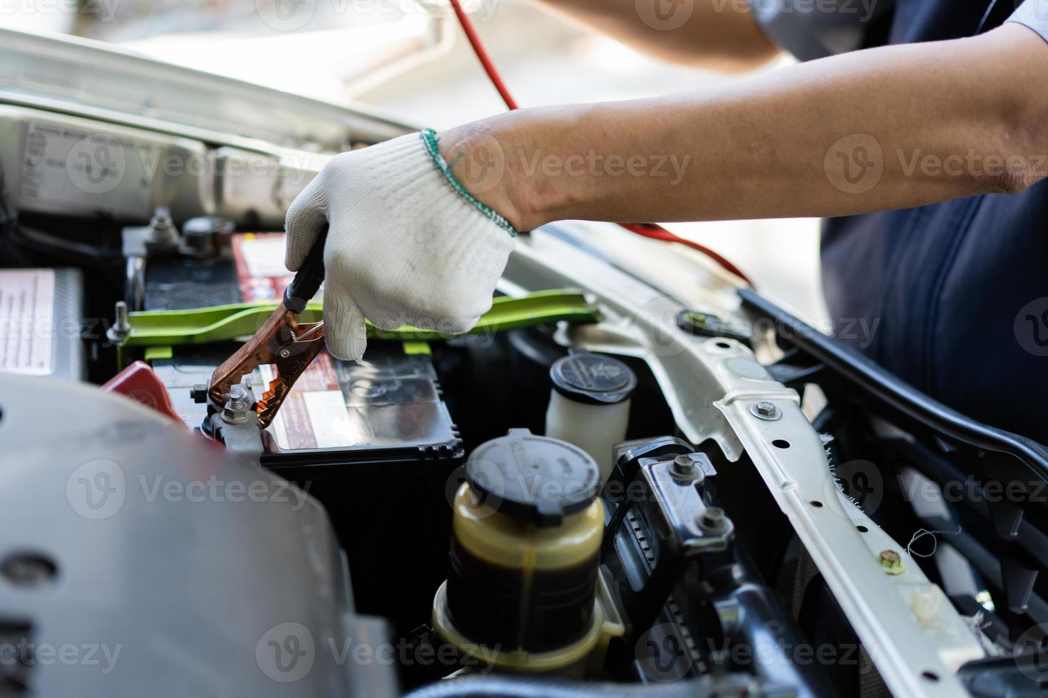 Close up and Selective focus of car mechanic holding battery electricity cables jumper for charging car battery, Services car engine machine concept photo