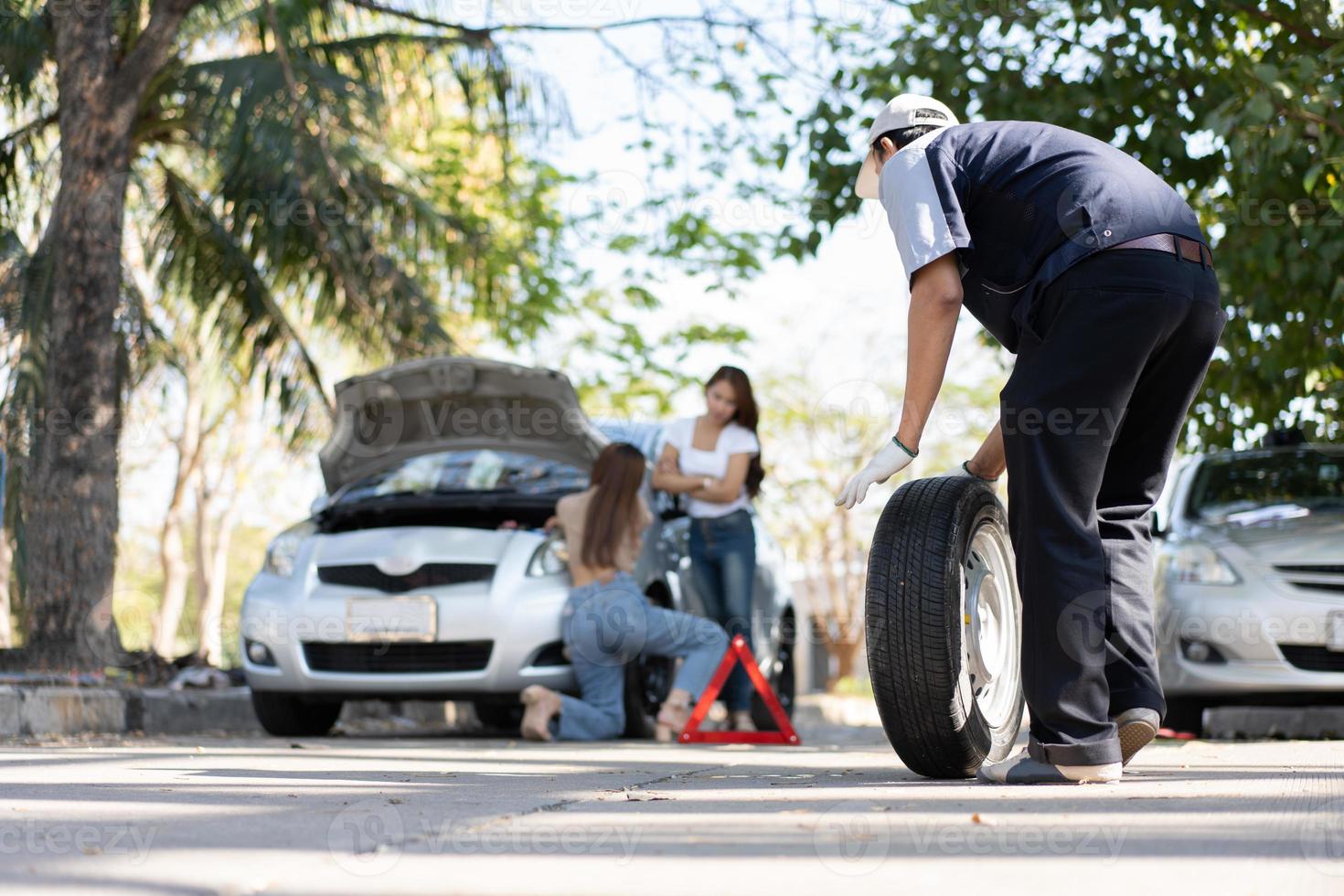 hombre mecánico experto en uniforme usando fuerza tratando de desatornillar las tuercas de los pernos de rueda y ayudar a una mujer a cambiar la rueda del camión en la carretera, servicio de camión, reparación, concepto de mantenimiento. foto