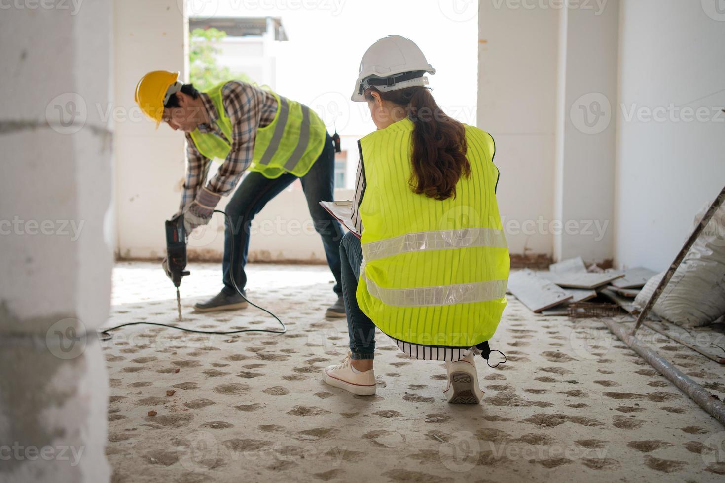Engineer checking worker using an electric jackhammer to drill perforator equipment making holes before pouring the floor to be strong at construction site, Concept of worker and residential building photo