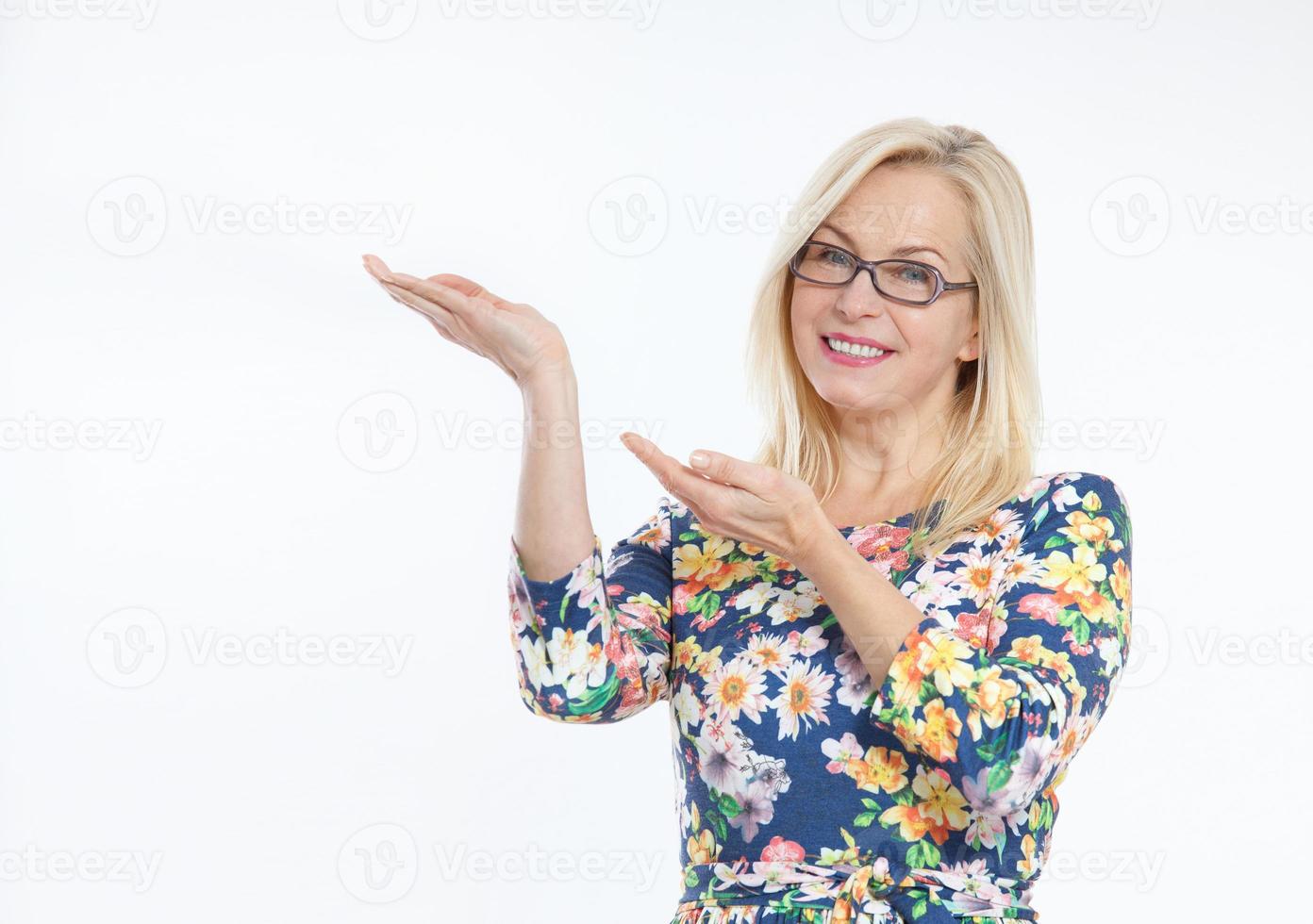 Friendly smiling middle aged woman pointing at copyspace isolated photo