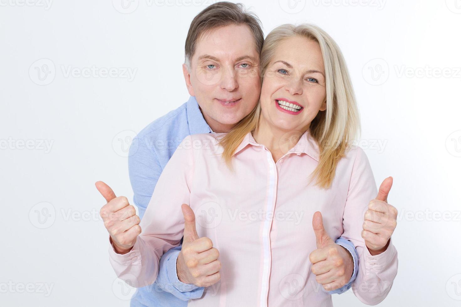 feliz pareja de mediana edad en abrazos y muestra el pulgar hacia arriba. foto