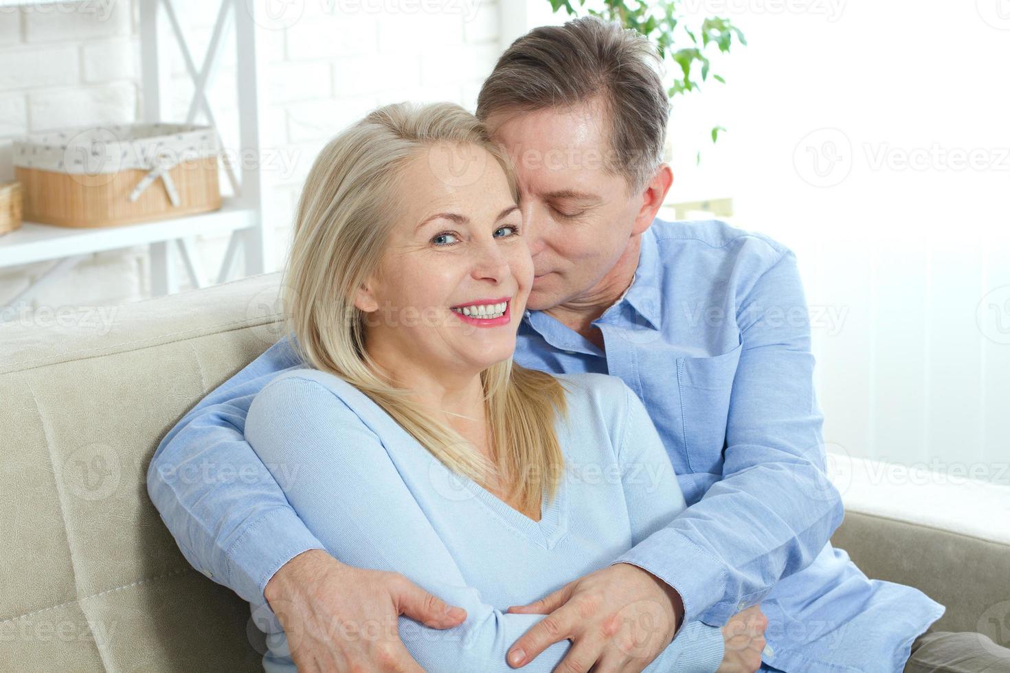 foto de primer plano de alegre, emocionado, feliz, felizmente feliz, con una sonrisa brillante y brillante, una mujer y un hombre rubios y atractivos, él la abraza por detrás y la besa