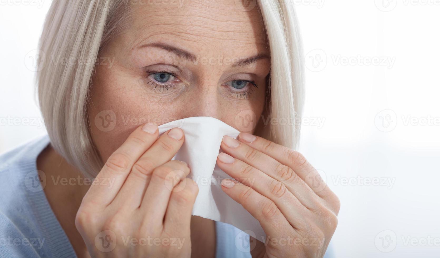 Concept coronavirus, covid-19 respiratory virus with indicating location of the pain. Healthcare, cold, allergy and sick woman blowing her runny nose in paper tissue. photo